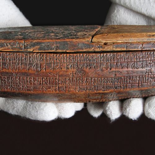 Närbild av den lockförsedda träasken, tryan, med runskrift.